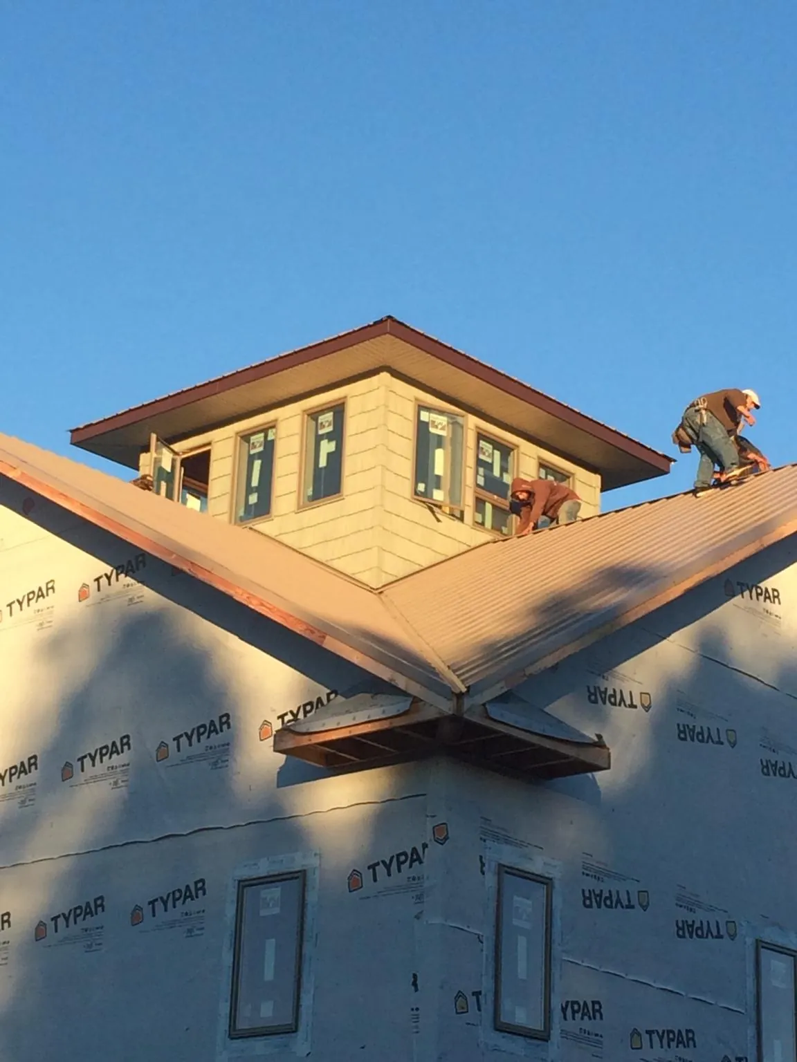 Roofers working around a rooftop cupola on a new metal roof at sunset — Roof Waterproofing in Deerfield by Roofing Brothers